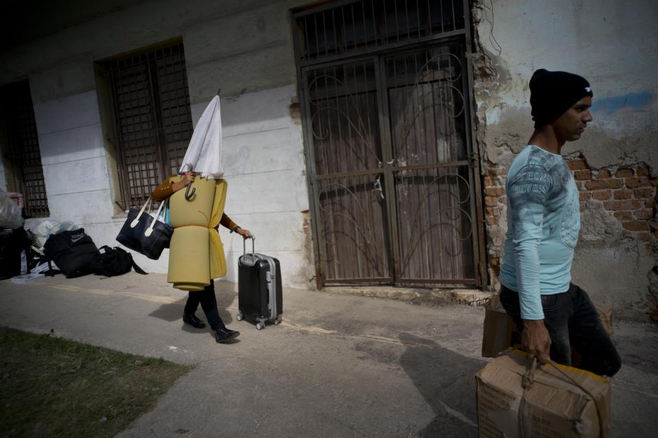 People affected by the destruction caused by the passing of a tornado, walk with their belongings to a bus to be taken to a shelter in Havana, Cuba, Monday, Jan. 28, 2019. Neighborhood brigades and teams of government workers hacked at fallen trees and hauled chunks of concrete out of collapsed homes Monday as the Cuban capital attempted to recover from what officials called the strongest tornado to hit Cuba in nearly 80 years.(AP Photo/Ramon Espinosa)