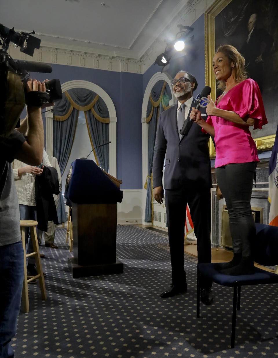 Reporter Kimberly Richardson stands on a chair to interview New York City Councilman Robert Cornegy, Jr., after he was awarded the Guinness World Record's for tallest male politician, Wednesday March 27, 2019, at City Hall in New York. (AP Photo/Bebeto Matthews)