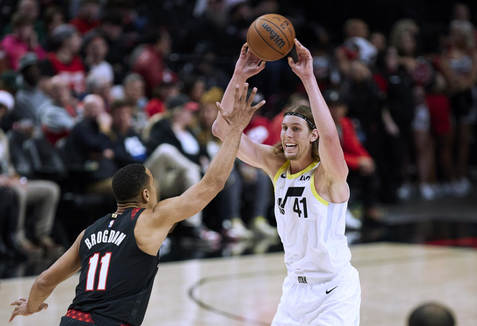 Utah Jazz forward Kelly Olynyk, right, passes the ball over Portland Trail Blazers guard Malcolm Brogdon during the second half of an NBA basketball game in Portland, Ore., Thursday, Dec. 14, 2023. (AP Photo/Craig Mitchelldyer)