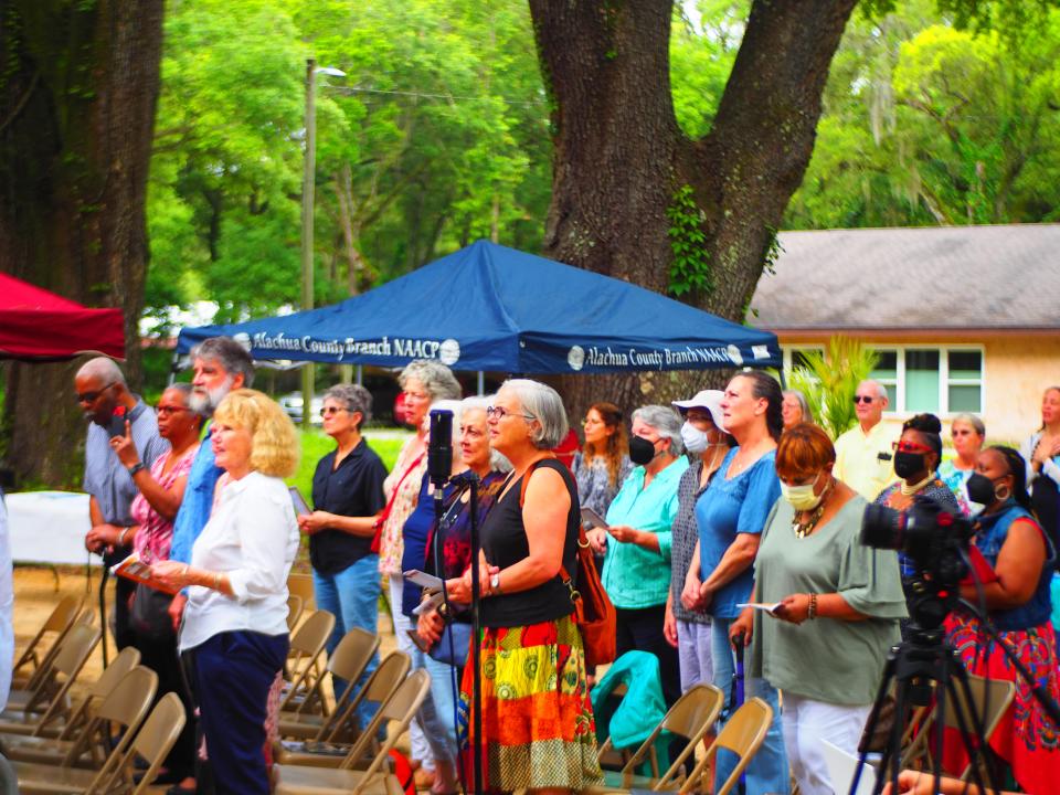 Community members stand during a soil collection ceremony as the names of individuals lynched in the Micanopy-Wacahoota area are read aloud.