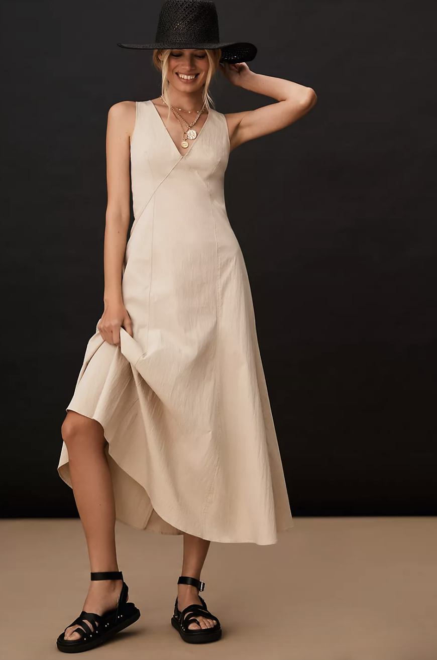 woman wearing black hat, black sneakers, By Anthropologie Sleeveless V-Neck A-Line Dress (photo via Anthropologie)
