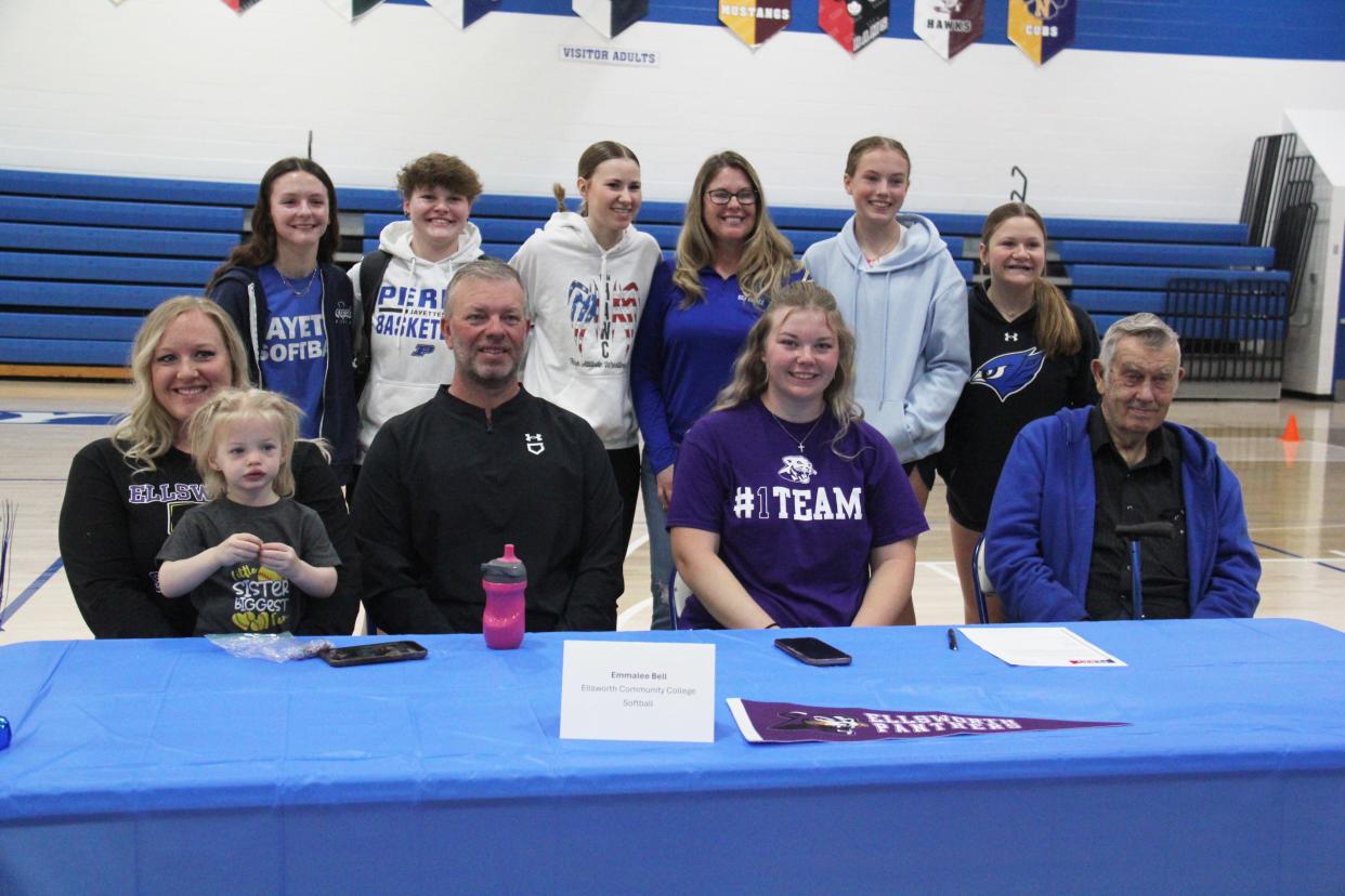 Emmalee Bell poses for a photo with her softball teammates and coach after committing to Ellsworth Community College during a celebratory signing day on Monday, May 6, 2024, in the Perry High School gym.