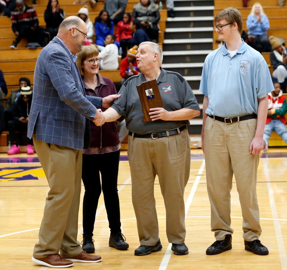 IHSAA commissioner Paul Neidig, left, shakes hands with John Overmyer after presenting Overmyer with the 2023-24 IHSAA Distinguished Media Service Award for District 1 at halftime of a boys basketball game between Riley and Clay Thursday, Jan. 18, 2024, at Clay High School. Also pictured are Overmyer's wife, Pam, and son, Josh.