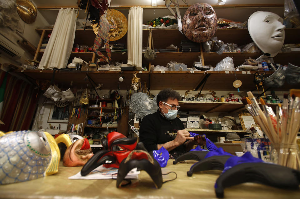 Venetian artisan mask maker Gualtiero Dall'Osto works in his workshop in Venice, Italy, Saturday, Jan. 30, 2021. In another year, masks would be an accepted sign of gaiety in Venice, an accessory worn for games, parties and crowds. Since the onset of the COVID-19 pandemic face masks are worn now to protect, not amuse. (AP Photo/Antonio Calanni)