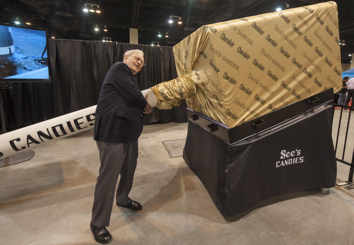IMAGE DISTRIBUTED FOR SEE'S - Berkshire Hathaway's Warren Buffett tries to lift a replica of a giant See's Candies lollypop, Saturday, May 3, 2014, at the Berkshire Hathaway Annual Shareholder's Meeting, in Omaha, Neb. (Photo by Dave Weaver/Invision for See's/AP Images)