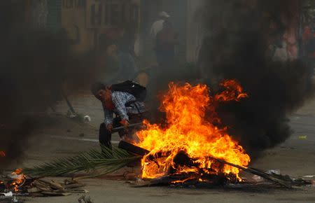 A protester from the National Coordination of Education Workers (CNTE) teachers’ union is seen next to a burning barricade after clashes with riot police officers during a protest against President Enrique Pena Nieto's education reform, near in the town of Nochixtlan, northwest of the state capital, Oaxaca City, Mexico June 19, 2016. REUTERS/Jorge Luis Plata