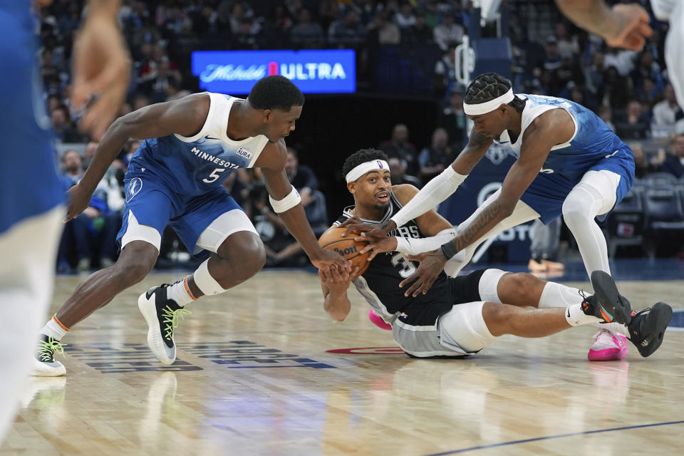 Minnesota Timberwolves guard Anthony Edwards, left, and forward Jaden McDaniels right, fight for the ball against San Antonio Spurs forward Keldon Johnson during the second half of an NBA basketball game, Tuesday, Feb. 27, 2024, in Minneapolis. (AP Photo/Abbie Parr)