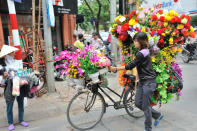 December 18: Where does she go ? by louis.foecy.fr. 'Weighed down by bouquets of flowers a woman heads to the Temple of Literature in Hanoi, Vietnam. Let's follow her explosion of colours and joy!'