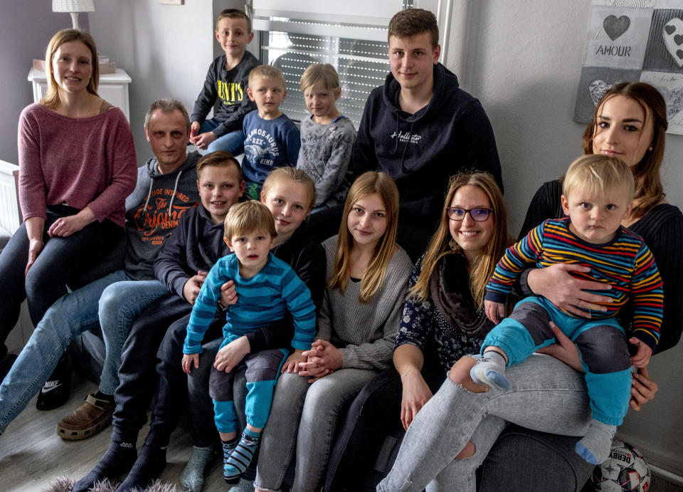 Katja Heimann, her husband and their eleven children sit on a sofa in their home in Eisemroth, central Germany, Thursday, March 25, 2021. One year into the coronavirus pandemic, Katja Heimann is still trying to keep her spirits up - despite several lockdowns and months of teaching seven of her children in home schooling. (AP Photo/Michael Probst)