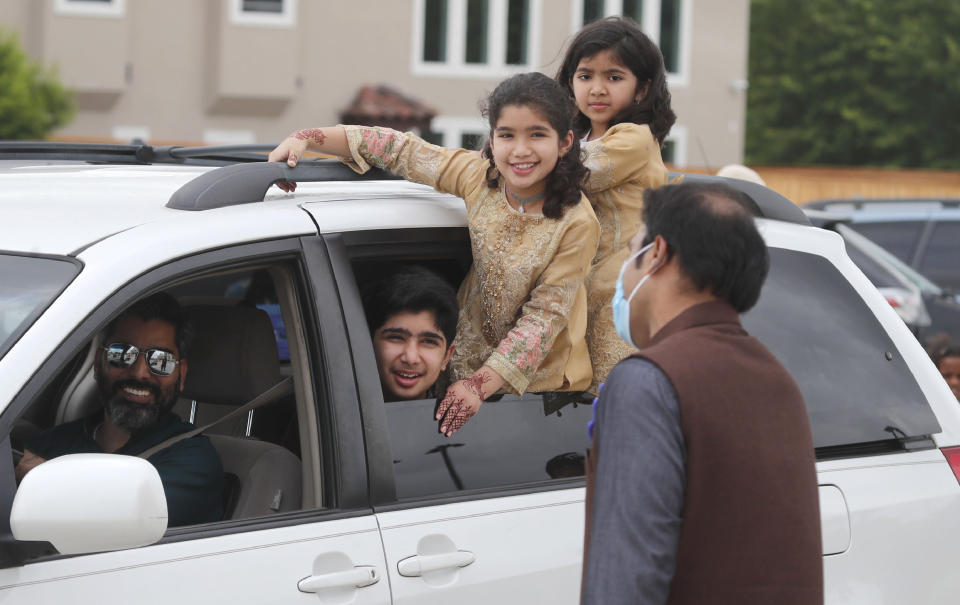 A family looks out from their vehicle during an Eid al-Fitr drive through celebration outside a closed mosque in Plano, Texas, Sunday, May 24, 2020. Many Muslims in America are navigating balancing religious and social rituals with concerns over the virus as they look for ways to capture the Eid spirit this weekend. (AP Photo/LM Otero)