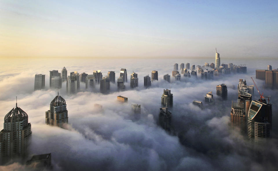 FILE - In this Monday, Oct. 5, 2015 file photo, a thick blanket of early morning fog partially shrouds the skyscrapers of the Marina and Jumeirah Lake Towers districts of Dubai, United Arab Emirates. Travel agencies in countries across the Middle East and Africa say the United Arab Emirates has temporarily halted issuing new visas to their citizens, a so-far unexplained ban on visitors amid both the coronavirus pandemic and as the UAE normalizes ties with Israel. (AP Photo/Kamran Jebreili, File)