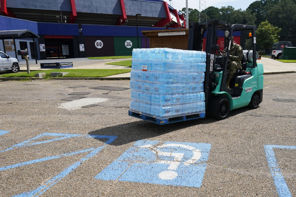 A Mississippi National Guardsman drives a water laden pallet through the parking lot of Smith Wills Stadium in Jackson, Miss., Friday, Sept. 2, 2022. The stadium is one of several water distribution sites the Guard is handling, in addition to those from private companies, churches and social organizations. (AP Photo/Rogelio V. Solis)