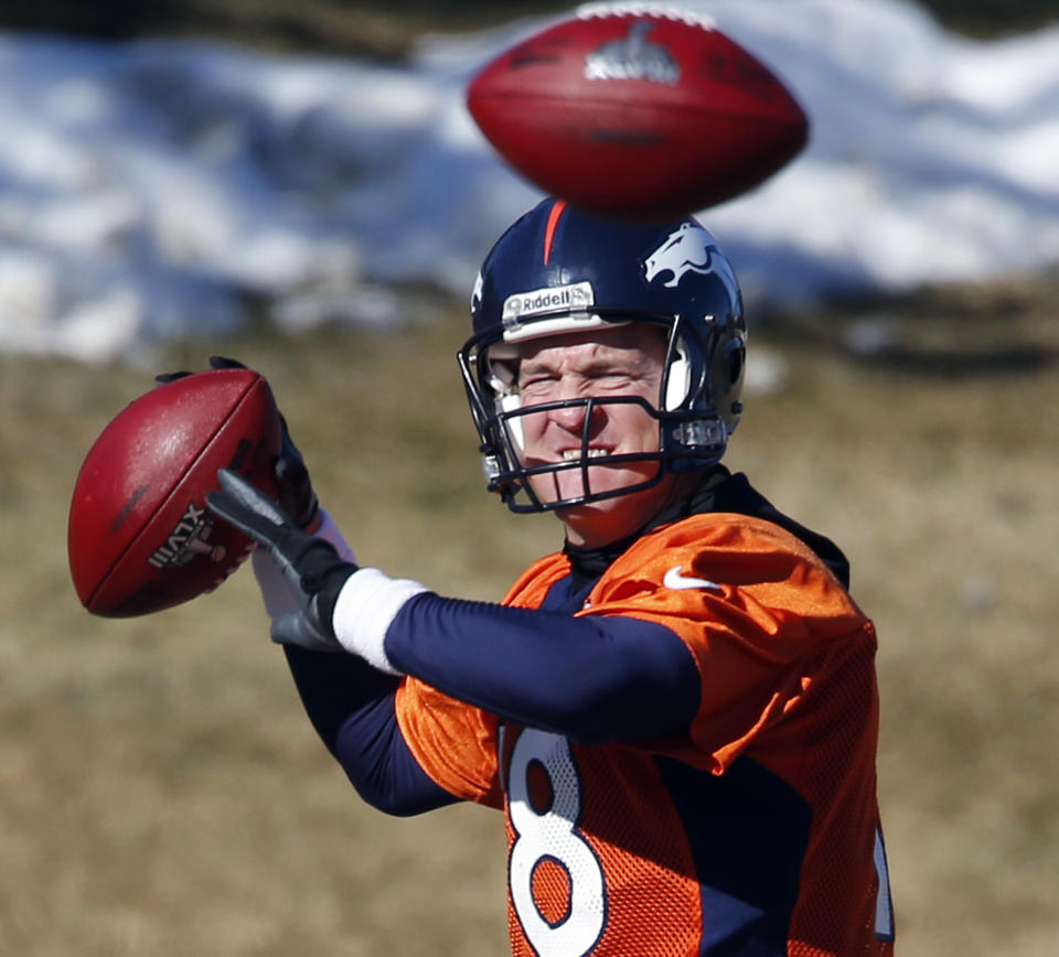 An extra football crosses in front of Denver Broncos quarterback Peyton Manning as he throws another during NFL football practice at the team's training facility in Englewood, Colo., on Friday, Jan. 24, 2014. The Broncos are scheduled to play the Seattle Seahawks in Super Bowl XLVIII on Feb. 2. (AP Photo/Ed Andrieski)