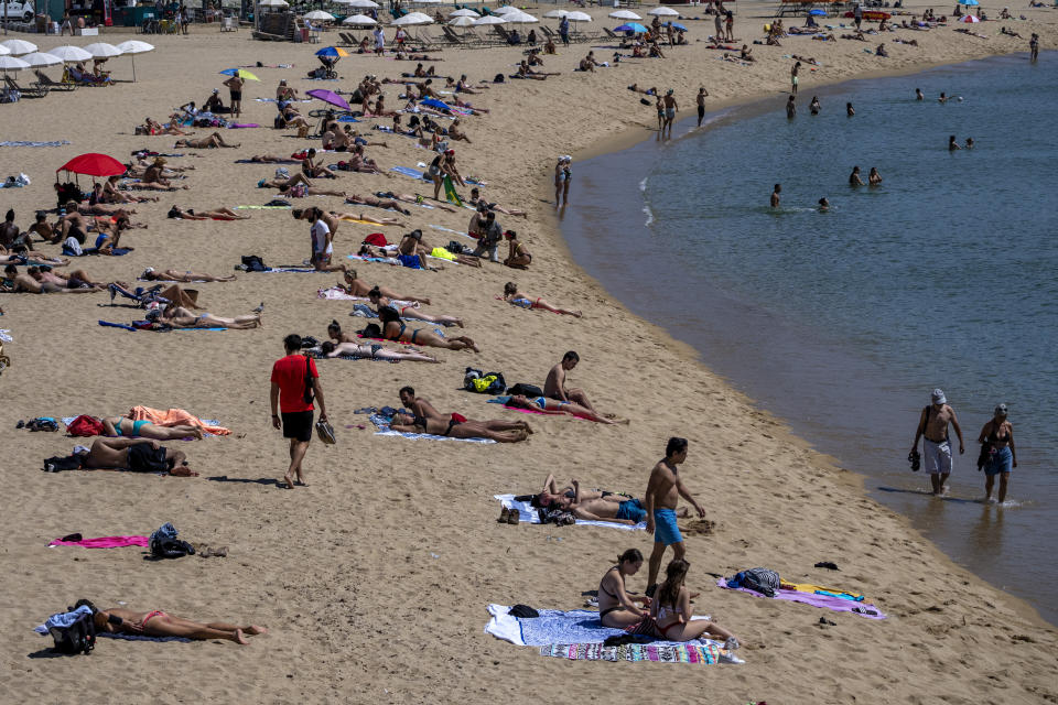 People sunbathe on the beach in Barcelona, Spain, Tuesday, June 8, 2021. Spain is jumpstarting its summer tourism season by welcoming vaccinated visitors from most countries as well as European visitors who can prove they are not infected with coronavirus. (AP Photo/Emilio Morenatti)