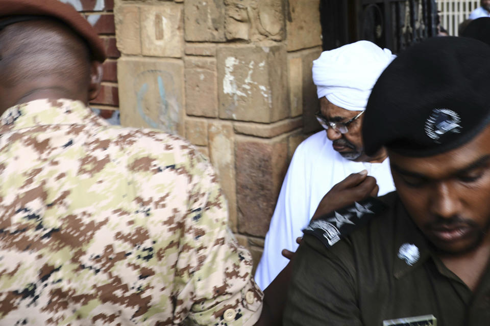 Sudan's ousted president Omar al-Bashir is escorted into a vehicle as he returns to prison following his appearance before prosecutors over charges of corruption and illegal possession of foreign currency, in Khartoum the capital of Sudan on Sunday June 16, 2019. The deposed strongman has been held under arrest in the capital since the military removed him from power in April amid mass public protests against his 30-year rule.(AP Photo/Mahmoud Hjaj)