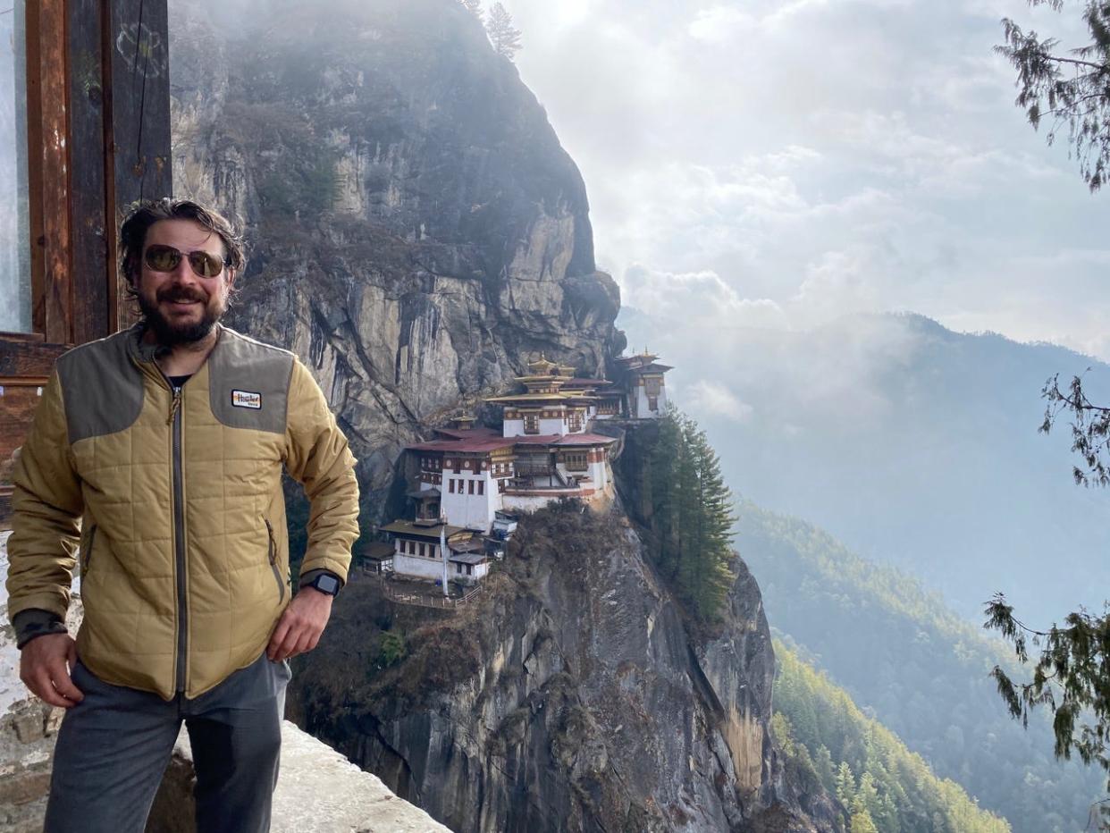 Ash Jurberg in Bhutan in front of Tigers Nest Monastery