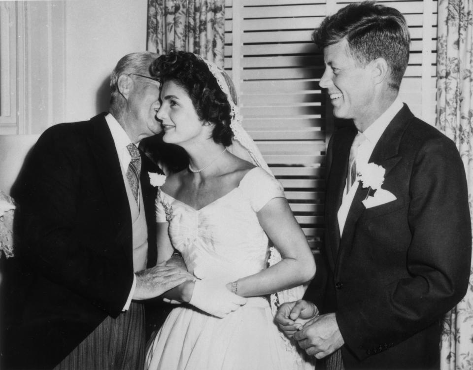 Joseph Kennedy (1888 - 1969) whispers to his new daughter-in-law Jacqueline Bouvier (1929 - 1994) on her wedding day as her husband John F. Kennedy (1917 - 1963) looks on, smiling, Newport, Rhode Island, September 12, 1953. (Photo by Hulton Archive/Getty Images)