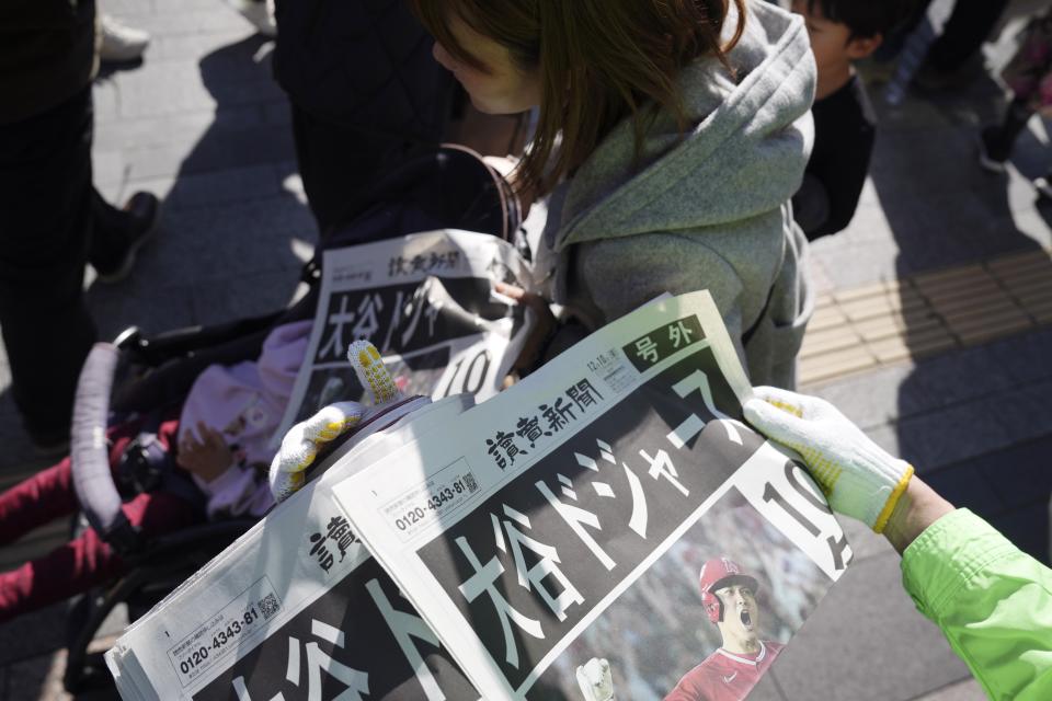 A staff distributes an extra edition of the Yomiuri Shimbun newspaper reporting on Shohei Ohtani to move to the Los Angeles Dodgers Sunday, Dec. 10, 2023, in Tokyo. Ohtani agreed to a record $700 million, 10-year contract with the Dodgers.(AP Photo/Eugene Hoshiko)