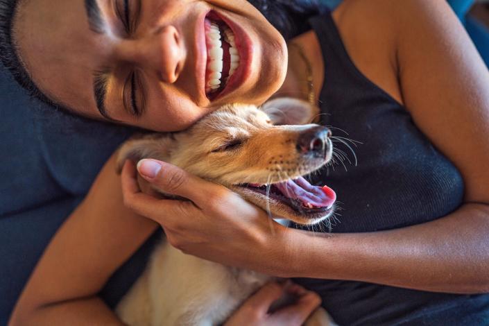 woman joyfully cuddling her happy dog; how to bond with your dog