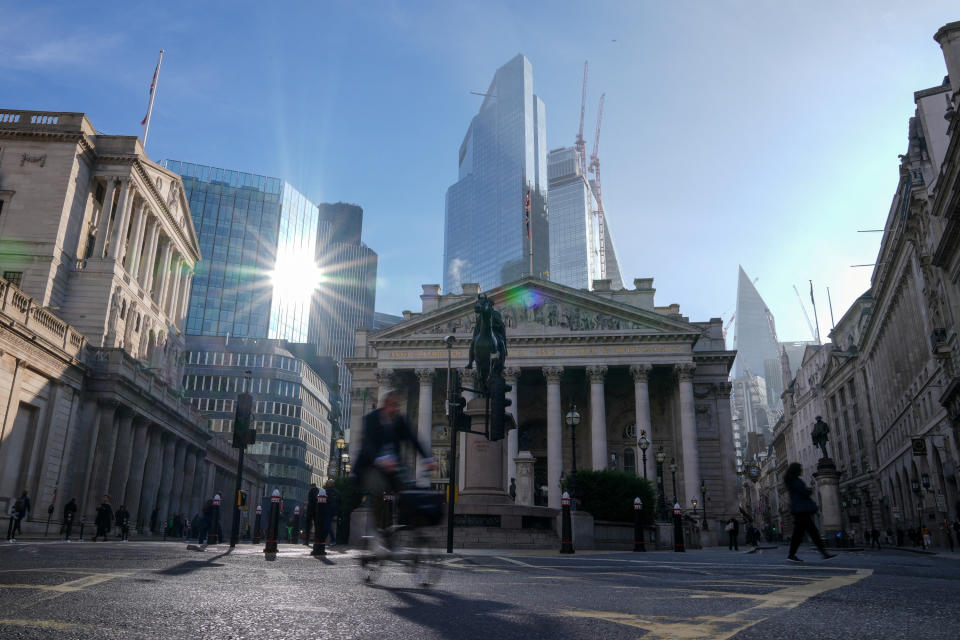 A man cycles past the Bank of England and Financial District in London