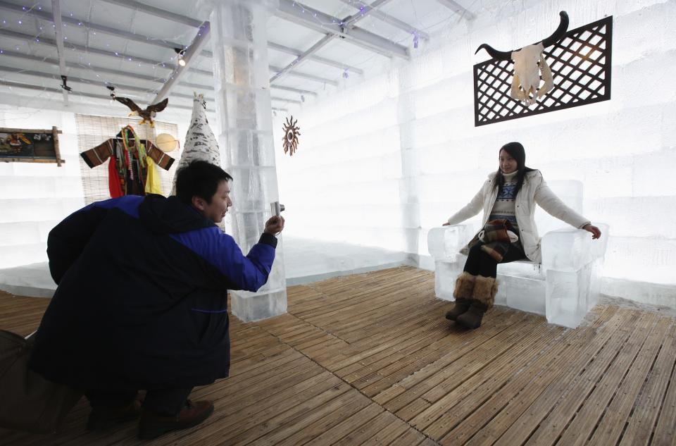 A couple takes a picture with a chair made of ice at the Ice Palace in Shangri-La Hotel in Harbin