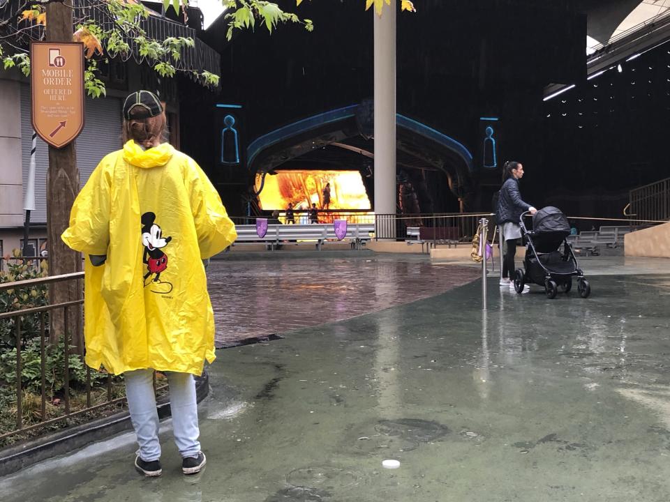 A few visitors stand in the rain at Disneyland in Anaheim, Calif., Friday, March 13, 2020. Disneyland is closing its doors for the rest of the month, shuttering one of California's best-known attractions as the state hurries to stop the spread of the coronavirus. (AP Photo/Amy Taxin)