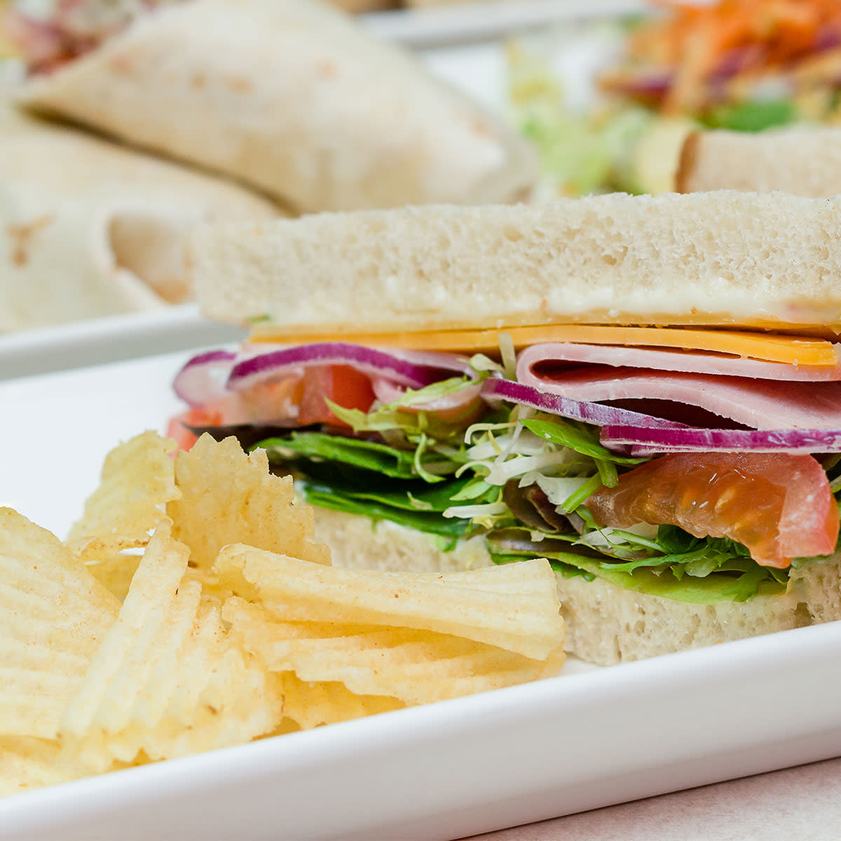 sandwich made with white bread and side of potato chips