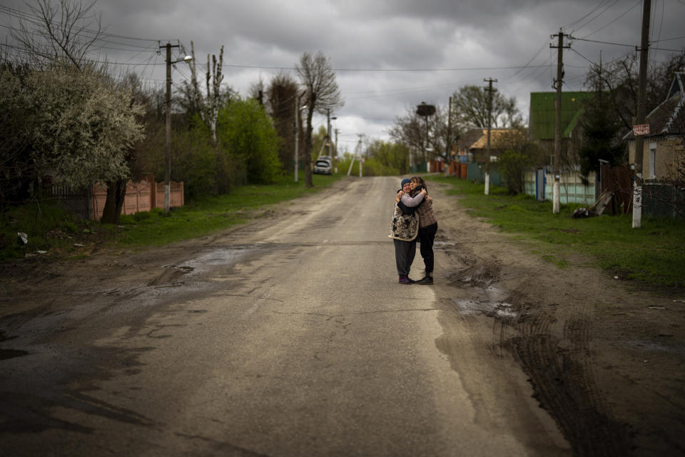 Tetiana Boikiv, 52, right, meets and hugs her neighbor, Svitlana Pryimachenko, 48, during a funeral service for her husband, Mykola "Kolia" Moroz, 47, in the Ukrainian village of Ozera, near Bucha, on Tuesday, April 26, 2022. Russian soldiers took Kolia from his house on March 15. He was tortured and shot, his body found two weeks later in a village 15 kilometers (9 miles) away where Russians set up a major forward operating base for their assault on the capitol, Kyiv. (AP Photo/Emilio Morenatti)