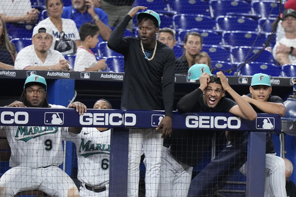 Miami Marlins players watch from the dugout during the bottom of the ninth inning of a baseball game against the Milwaukee Brewers, Friday, Sept. 22, 2023, in Miami. (AP Photo/Wilfredo Lee)