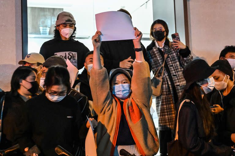 La gente muestra papeles en blanco como forma de protesta, se ve en una pared mientras se reúnen en una calle en Shanghai el 27 de noviembre de 2022