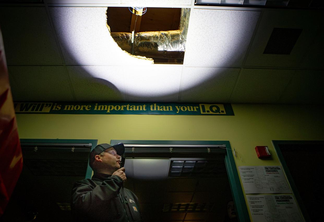 Springfield Public Schools Chief Operations Officer Brett Yancey shines a flashlight on a fallen roof tile amid a power outage at Agnes Stewart Middle School as the district assesses damage to buildings on Jan. 18 in Springfield.