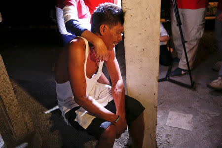 A man is comforted by his wife after their seven-year-old daughter was found killed at Tugatog public cemetery, in Manila, Philippines early October 22, 2016. REUTERS/Damir Sagolj