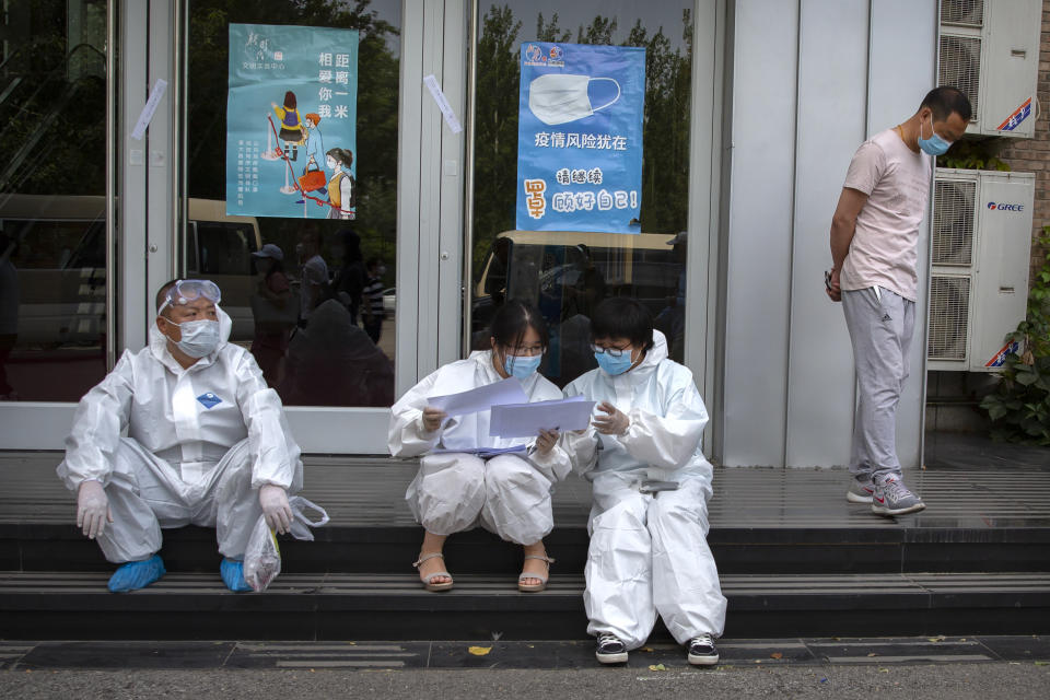 Workers in protective suits review paperwork at a COVID-19 testing site for those who were potentially exposed to the coronavirus outbreak at a wholesale food market in Beijing, Wednesday, June 17, 2020. As the number of cases of COVID-19 in Beijing climbed in recent days following an outbreak linked to a wholesale food market, officials announced they had identified hundreds of thousands of people who needed to be tested for the coronavirus. (AP Photo/Mark Schiefelbein)