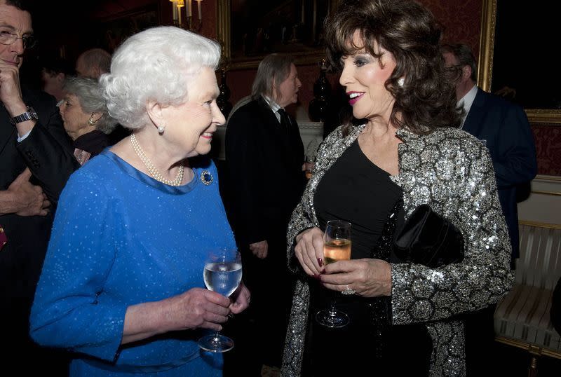<p>Joan Collins isn’t the muted outfit type—and the silver metallic jacket she wore to meet the Queen is proof. She almost upstaged the Queen, but everyone knows that’s impossible.</p>