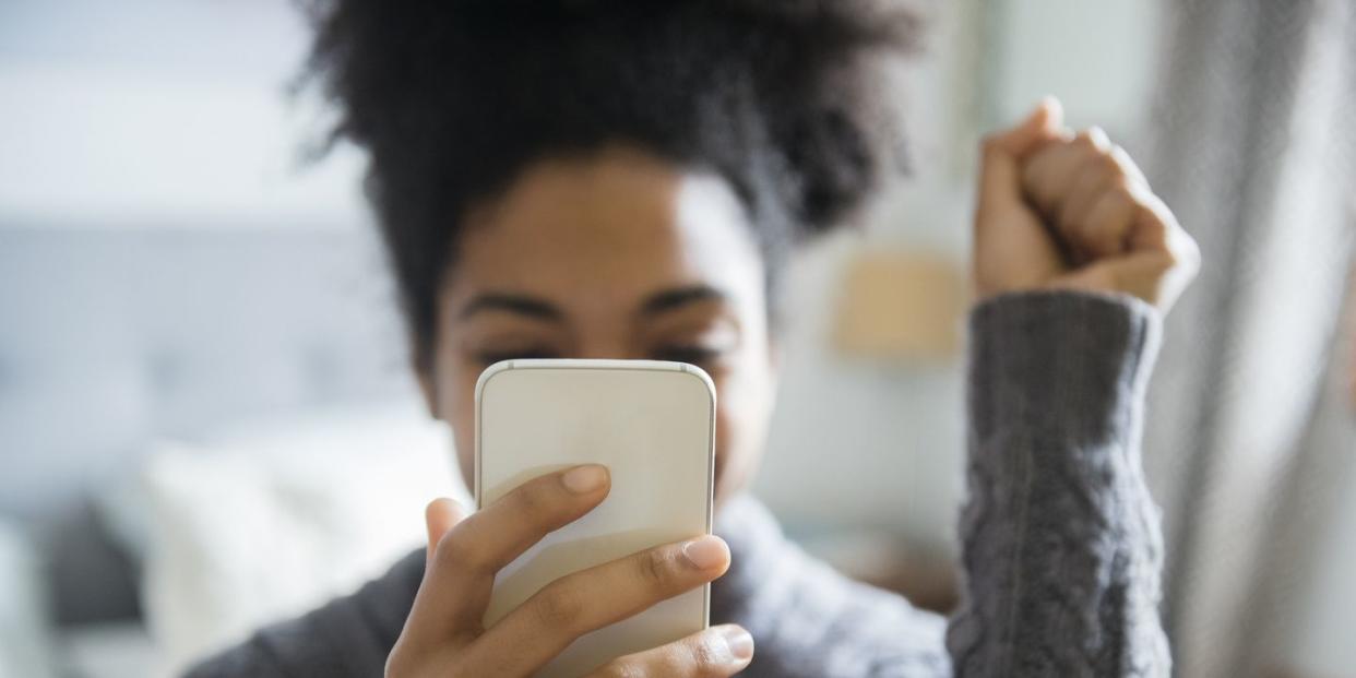 woman holding smart phone in front of face with hand up