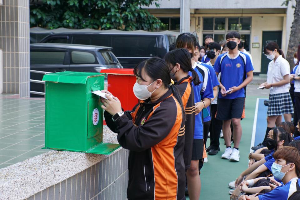 亞餐學生將寫好的卡片投入仿真郵筒道具中。（記者施春瑛攝）