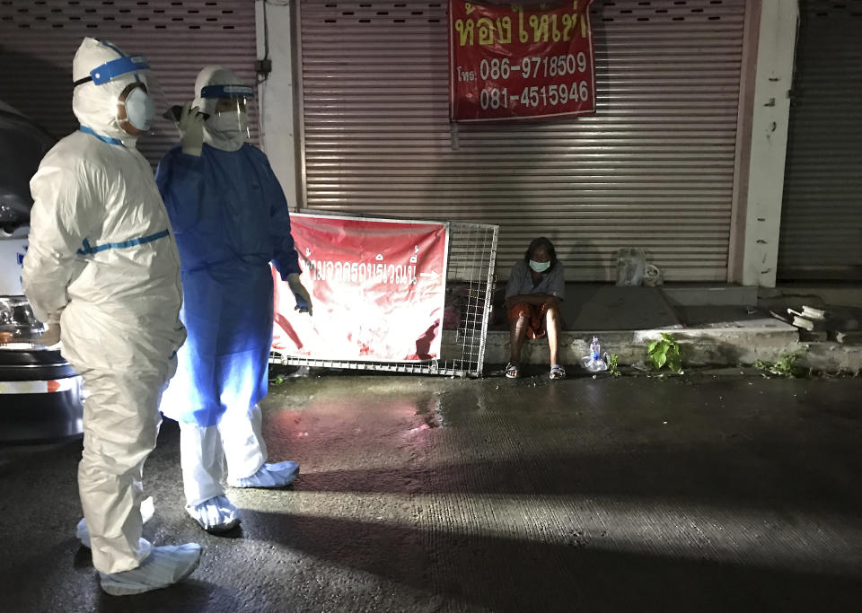 Volunteers from the "Saimai Will Survive" group in protective gear prepare to test a homeless woman with COVID-19 symptoms Saturday, July 24, 2021, in Bangkok, Thailand. As Thailand's medical system struggles beneath a surge of coronavirus cases, ordinary people are helping to plug the gaps, risking their own health to bring care and supplies to often terrified, exhausted patients who've fallen through the cracks. (AP Photo/Tassanee Vejpongsa)