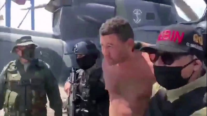 Venezuelan soldiers in balaclavas move a suspect from a helicopter after what Venezuelan authorities described was a "mercenary incursion", at an unknown location in this still frame obtained from Venezuelan government TV video