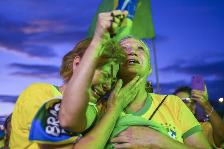 Simpatizantes de Jair Bolsonaro se abrazan mientras escuchan los resultados parciales después del cierre de urnas en la segunda vuelta de las elecciones presidenciales en Brasilia, Brasil, el domingo 30 de octubre de 2022. 