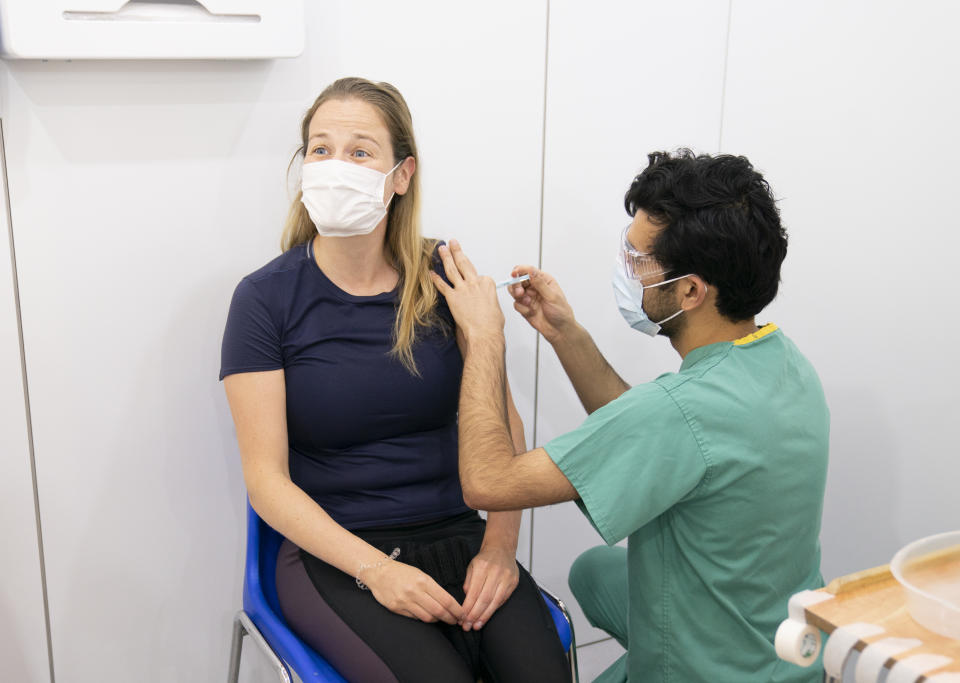 Amir Saemi (right) administers a booster coronavirus vaccine to Kayleigh Kitson (left) at a Covid vaccination centre at Elland Road in Leeds, as the booster vaccination programme continues across the UK. Picture date: Tuesday December 21, 2021.