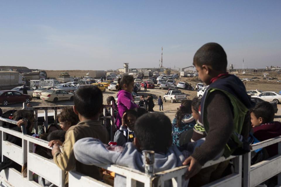 Children wait on the back of a pick up truck outside the Khazer checkpoint on the road to Mosul, Tuesday Feb. 7, 2017. The United Nations says some 30,000 people have returned to neighborhoods in Mosul retaken from the Islamic State group since the operation to push the militants from the city was officially launched in October. (AP Photo/Bram Janssen)