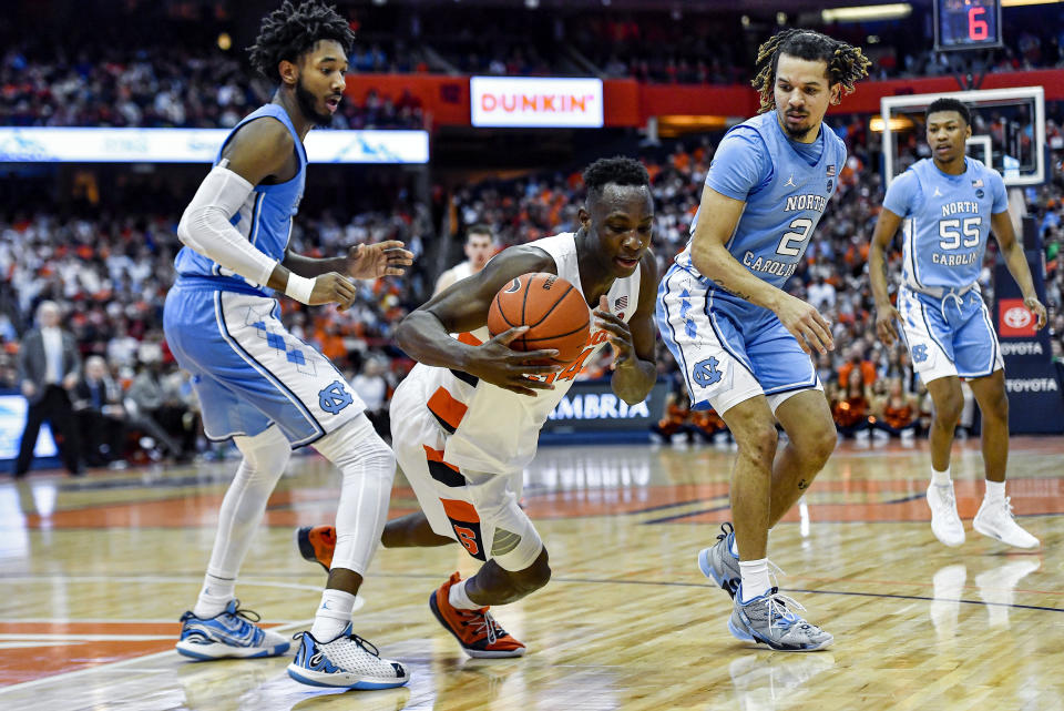 Syracuse forward Bourama Sidibe, center, goes to the ground with the ball between North Carolina guard Leaky Black, left, and guard Cole Anthony during the second half of an NCAA college basketball game in Syracuse, N.Y., Saturday, Feb. 29, 2020. North Carolina defeated Syracuse 92-79. (AP Photo/Adrian Kraus)