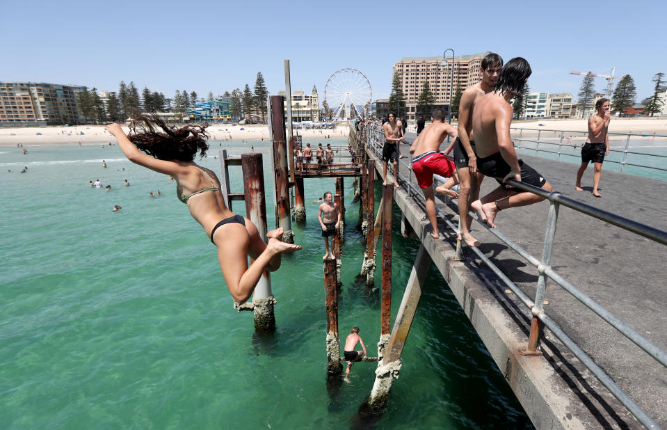 Teens jumping off the pier at Glenelg beach in Adelaide on a hot day. Source: AAP