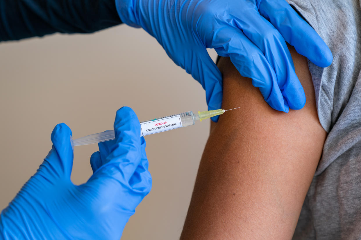 This picture depicts a young female clinician using a syringe to inject a concept COVD-19 liquid vaccine into a young girl patient during the Phase 3 vaccination human trials.