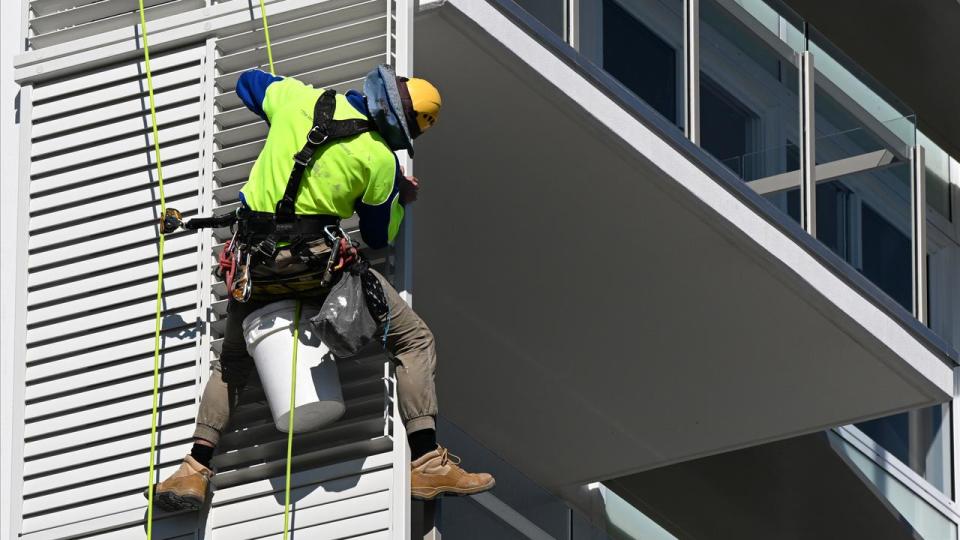 A construction worker working on the side of a new apartment building