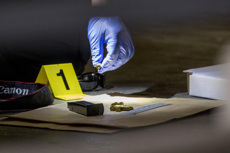 Police officers photograph bullets and a firearm magazine at a crime scene following a shooting at the parking garage for the Fashion Centre at Pentagon City, also known as Pentagon City Mall, Monday, July 1, 2019, in Arlington. (AP Photo/Andrew Harnik)