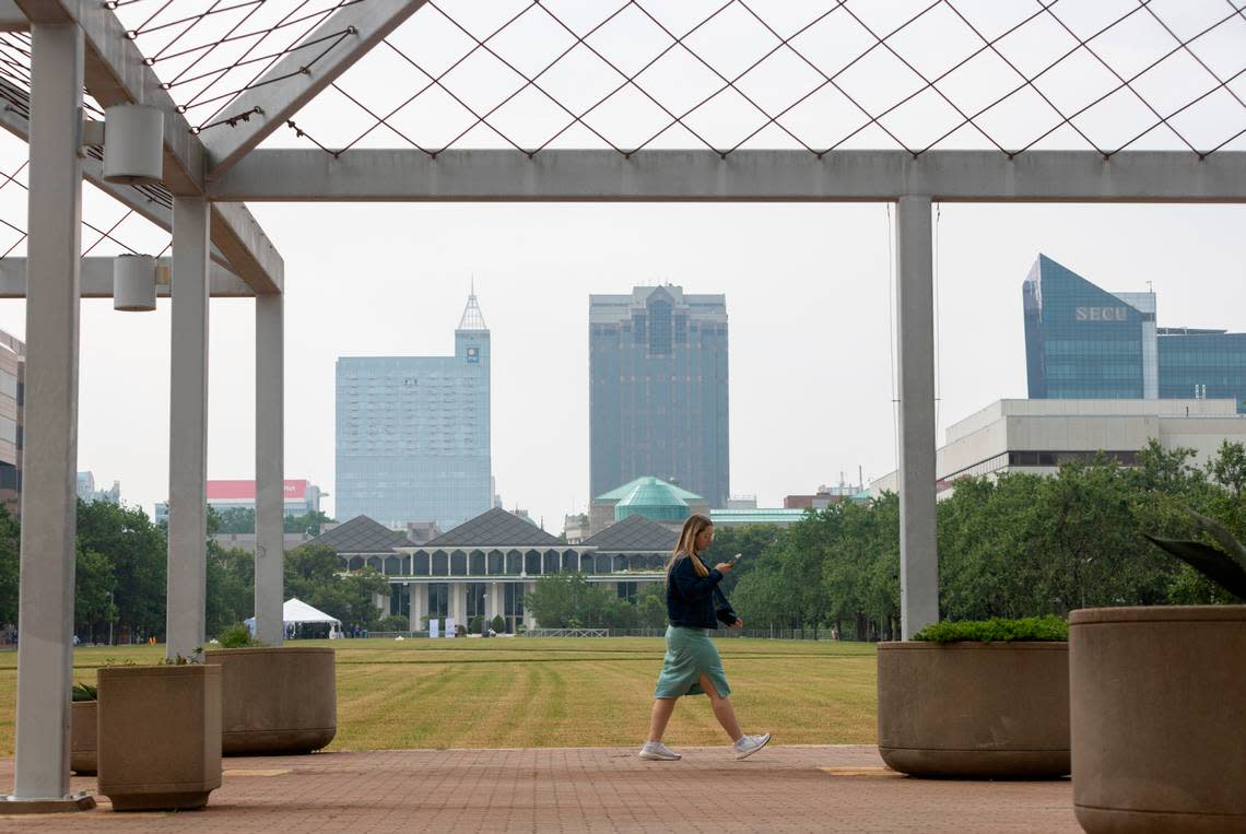State employee Corrie Byrd walks around the Halifax Mall, behind the North Carolina General Assembly building, with a hazy downtown skyline backdrop, as smoke from Canadian wildfires moves across the country on Wednesday, June 7, 2023 in Raleigh, N.C.