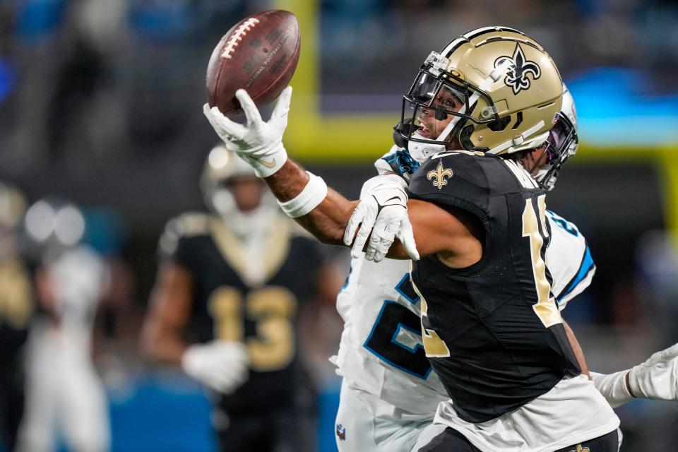 New Orleans Saints wide receiver Chris Olave (12) keeps his eye on the ball making a catch defended by Carolina Panthers cornerback CJ Henderson (23) during the second half at Bank of America Stadium.