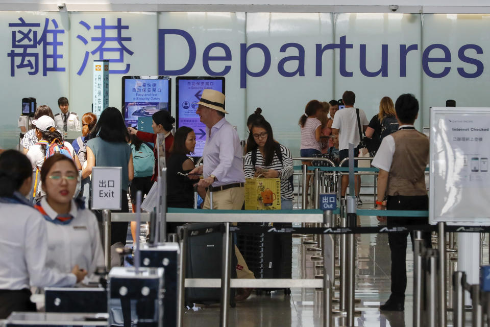 Airport staff help travellers near the departure gate at the airport in Hong Kong, Wednesday, Aug. 14, 2019. Flight operations resumed at the airport Wednesday morning after two days of disruptions marked by outbursts of violence highlighting the hardening positions of pro-democracy protesters and the authorities in the Chinese city that's a major international travel hub. (AP Photo/Vincent Thian)