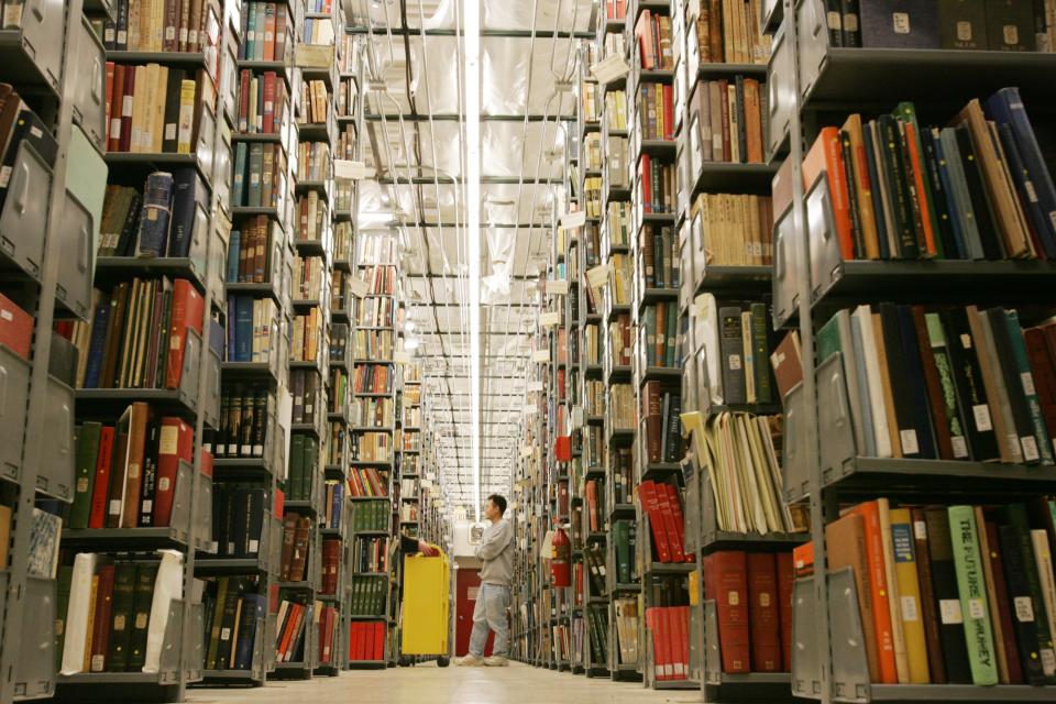 FILE-In this Monday, Dec. 13, 2004, file photo, Vince Lee, 34, a library staffer at the University of Michigan's Buhr Shelving Facility, stands among the 2.4 million books that will be digitized in Ann Arbor, Mich. Google and U.S. publishers settled a longstanding dispute over Google's book-scanning project Thursday, Oct. 4, 2012. Google already has scanned more than 20 million books. Publishers and authors sued, saying the project violated their copyrights. (AP Photo/The Detroit News, Mandi Wright)